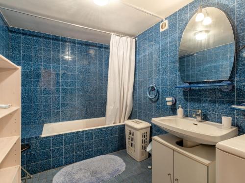 ein blau gefliestes Bad mit einem Waschbecken und einer Badewanne in der Unterkunft Apartment Petit bois by Interhome in Saint-Jean-de-Luz