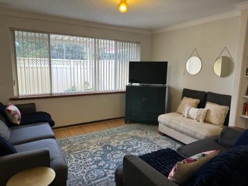 Comfort Inn Getaway في بيرث: غرفة معيشة مع أريكة وتلفزيون بشاشة مسطحة