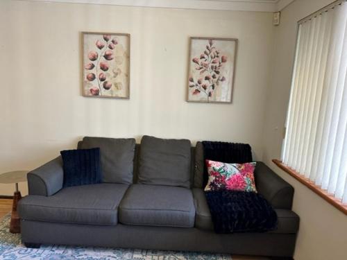 a living room with a gray couch and two pictures at Comfort Inn Getaway in Perth