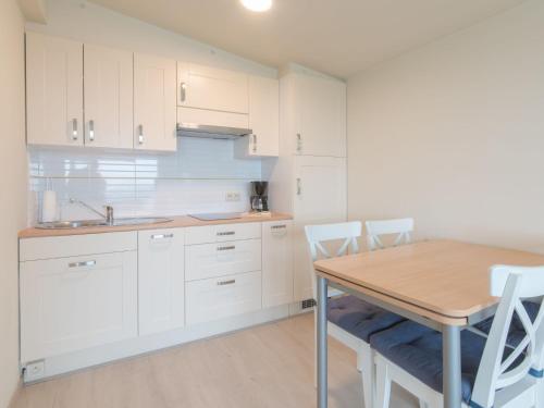 a kitchen with white cabinets and a table and chairs at Studio High in the sky with amazing views by Interhome in De Haan
