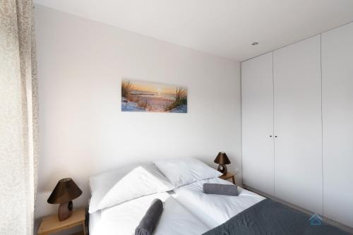 um quarto branco com uma cama e um quadro na parede em Uroda Morza by 3City Rentals em Gdynia
