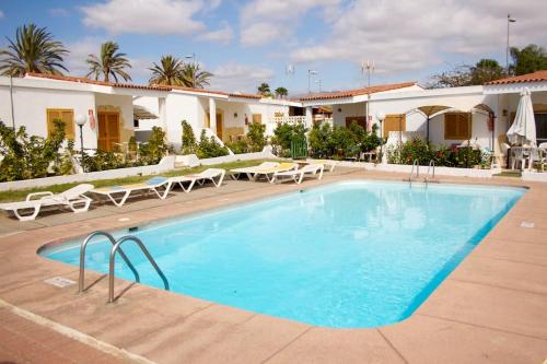 uma grande piscina com cadeiras e um edifício em Precioso Bungalow 1 em Playa del Inglés