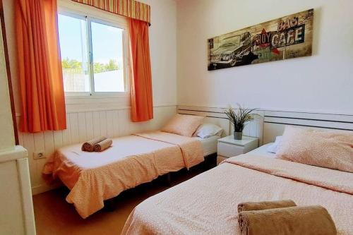 a bedroom with two beds with orange curtains and a window at Precioso Bungalow 1 in Playa del Ingles