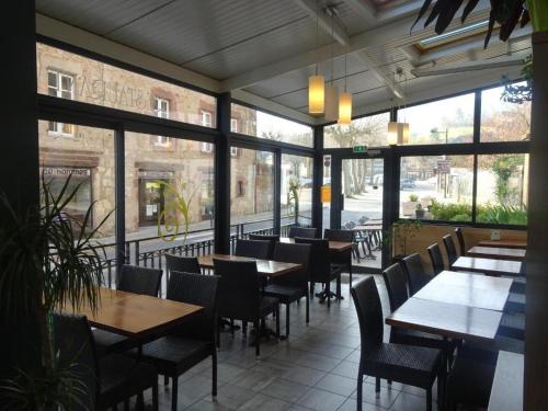 ein Restaurant mit Tischen, Stühlen und Fenstern in der Unterkunft La Citadelle in La Canourgue