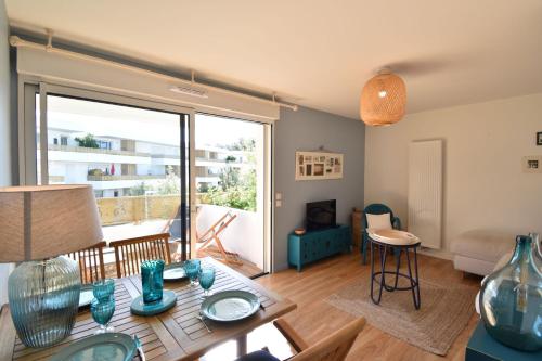 un salon avec une table et une grande fenêtre dans l'établissement Maréchal Foch - Magnifique appartement avec une spacieuse terrasse Capbreton, à Capbreton