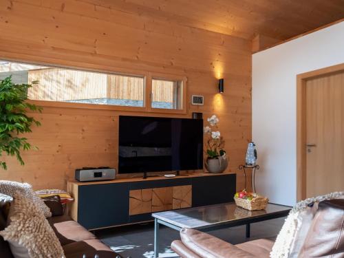 a living room with a television and a table at Chalet Les Penguins by Interhome in Nendaz