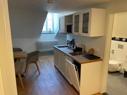 a kitchen with white cabinets and a table and a dining room at Palmbräu Altstadt Appartments in Heidelberg