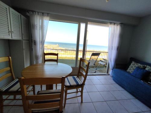 un salon avec une table et des chaises et un balcon dans l'établissement Port de Comberge - Studio 2P vue mer, à Saint-Michel-Chef-Chef