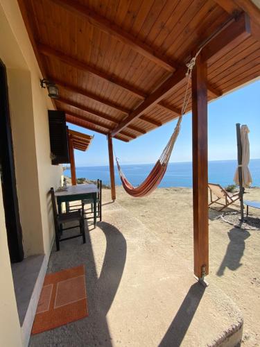 a patio with a table and a hammock on the beach at Gavdos Panorama in Gavdos