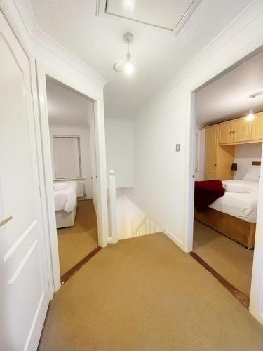 a room with two beds and a hallway with a door at Cozy Nights SVP Detached House in Nitshill