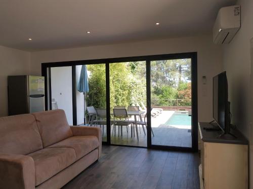 un salon avec un canapé et une porte coulissante en verre dans l'établissement Apartment Les Jardins d'Ève-F2 by Interhome, à Favone