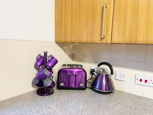 a kitchen counter with purple appliances on a counter top at Cozy Nights SVP Detached House in Nitshill