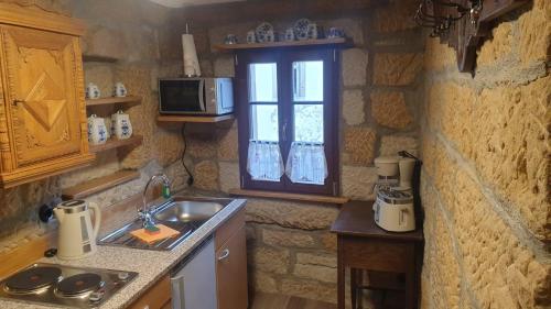 a kitchen with a sink and a microwave and a window at Das Ferienhaus Protze in Hohnstein