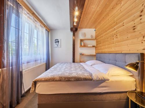 1 dormitorio con 1 cama con pared de madera en Chalet Krakonoš by Interhome en Mladé Buky