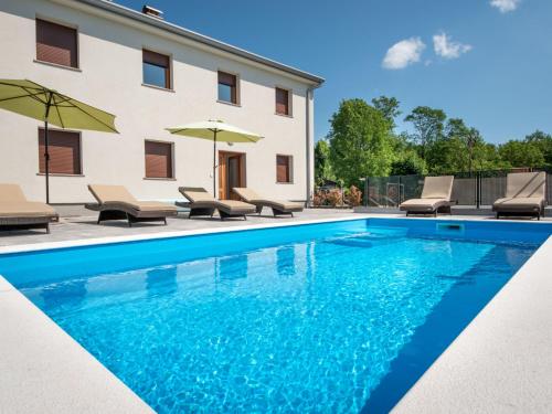 a pool with chairs and umbrellas next to a building at Holiday Home Nola by Interhome in Viskovo