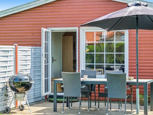 a table and chairs with an umbrella in front of a house at Holiday Home Amy - 150m from the sea in Funen by Interhome in Otterup