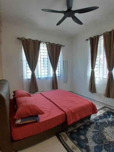 a bedroom with a red bed and a ceiling fan at Khayla Homestay in Kuah