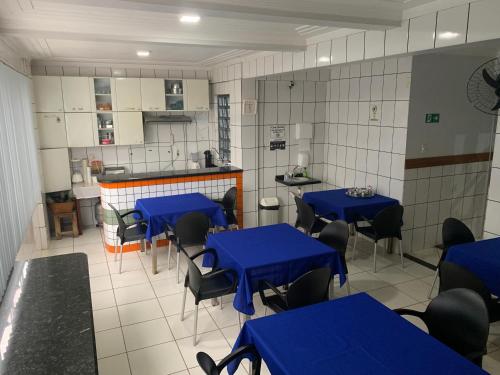 a room with blue tables and chairs and a kitchen at PREMIER HOTEL in Marabá