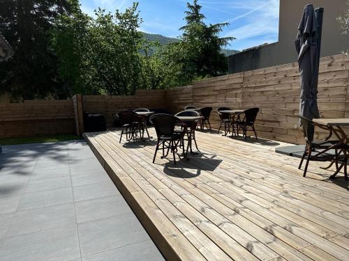 un patio con tavoli e sedie su una terrazza in legno di L'instant d'un séjour a Le Guâ