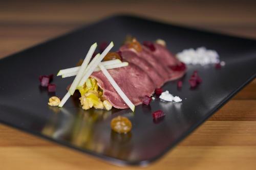 a piece of meat on a black plate with chopsticks at Penzion Repnik in Kamnik