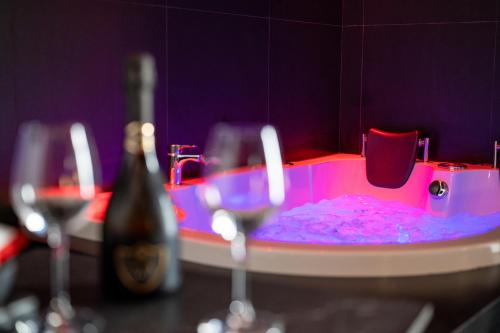 uma banheira roxa com dois copos de vinho e uma garrafa em Maximum hub suite&spa em Palermo