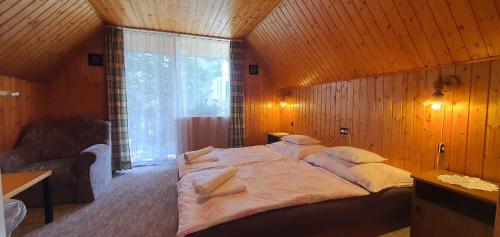 バラトンフェニヴェシュにあるApartment Balatonfenyves/Balaton 18389の木製の壁に大きなベッドが備わるベッドルーム1室
