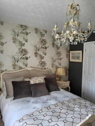 a bedroom with a large bed with a chandelier at Divine Cottage in Ballycastle