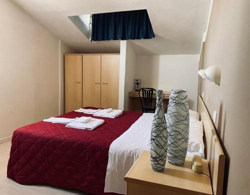 sypialnia z łóżkiem z czerwonym kocem i stołem w obiekcie Hotel New Primula w Rimini