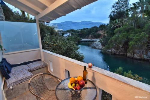 a table with a bottle of wine and fruit on a balcony at Sisi seaview apartments in Sissi