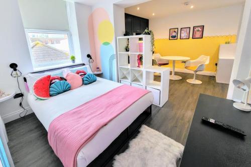 um quarto com uma cama com almofadas cor-de-rosa e azuis em Studio 38 - Urban Living in the Heart of Brighton em Brighton & Hove