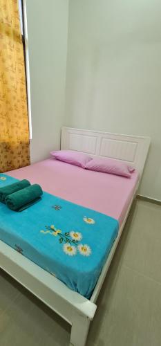 een wit bed met een blauwe deken erop bij OLIA MEDINA KERTEH 4 BILIK HOMESTaY in Kampong Kemaman