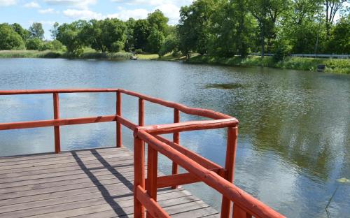 una barandilla roja junto a un río con árboles en Basic Apartment, en Līksna