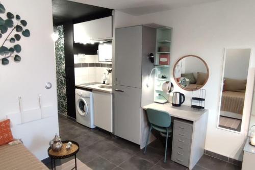 Elle comprend une petite cuisine avec un bureau et un miroir. dans l'établissement CADUCÉE Studio climatisé balcon ensoleillé parking proche Montpellier, à Grabels
