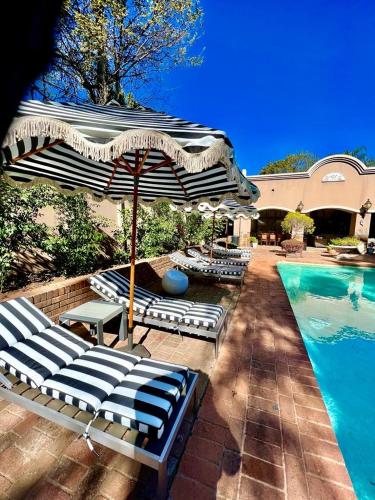 a group of chairs and an umbrella next to a pool at Forty 4 On Hoog in Polokwane