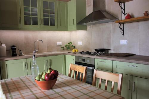 a kitchen with green cabinets and a table with a bowl of fruit at Avli House Vori in Vóroi