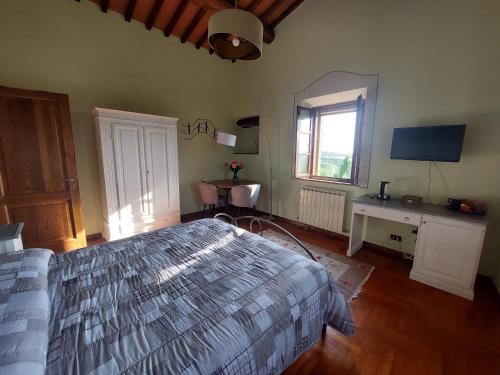 a bedroom with a bed and a desk and a television at Podere Cacchini in Pienza