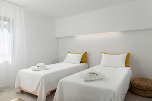 2 camas en una habitación con sábanas blancas y toallas en Lemoni House, en Ándros