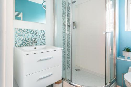 un bagno con un lavandino bianco e una doccia di Le Cottage de l'Hippodrome. a Lambersart