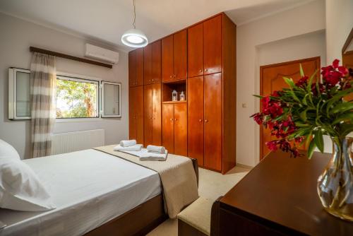 1 dormitorio con 1 cama y un jarrón con flores rojas en Serenitas, family house with great views, en Sfakiá