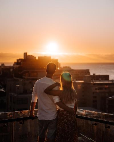 a man and a woman standing on a balcony watching the sunset at Home Suite Hotels Station House in Cape Town