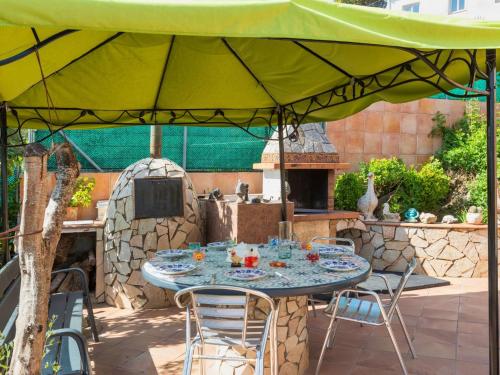 d'une terrasse avec une table et des chaises sous un parasol vert. dans l'établissement Holiday Home Aguilera by Interhome, à Maçanet de la Selva