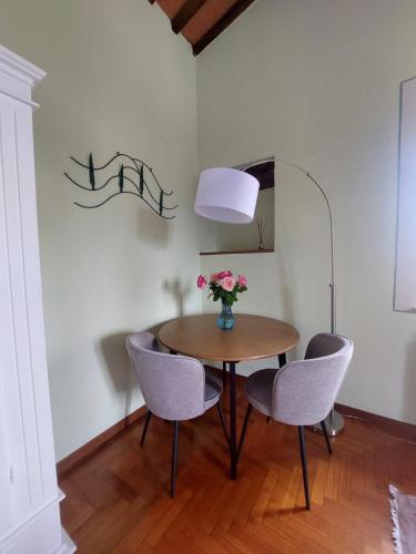 a dining room table with chairs and a vase of flowers at Podere Cacchini in Pienza