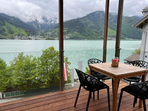 a table and chairs on a deck with a view of a lake at Apartment Residence Bellevue by Interhome in Zell am See