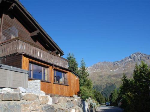 a wooden house with mountains in the background at Apartment Casa Hofer by Interhome in Valbella