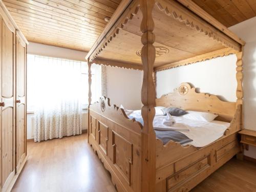 Ce lit en bois se trouve dans une chambre dotée d'un plafond en bois. dans l'établissement Apartment Hotel Restaurant La Tgoma by Interhome, à Lenz