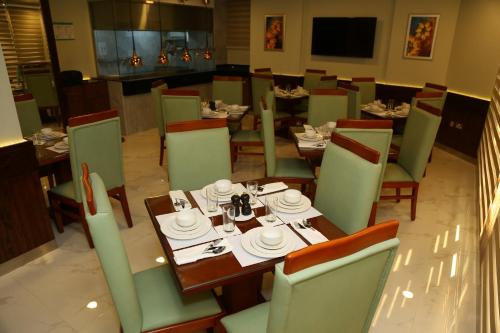 Grand Legacy Hotel Doha في الدوحة: غرفة طعام مع طاولة وكراسي مع أطباق عليها