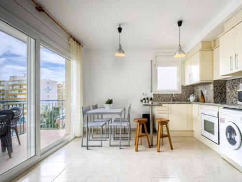 una cucina con tavolo e sedie e una grande finestra di Apartment Roca Llarga by Interhome a Roses