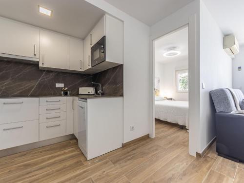 a kitchen with white cabinets and a room with a bed at Apartment Rodas-5 by Interhome in Salou