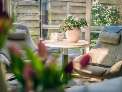 a room with two chairs and a table with a vase of flowers at Villa Domicile adoré by Interhome in Ostend