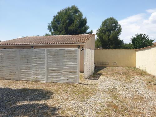 a building with a garage next to a fence at Canal du Midi Argeliers Gîte 4 personnes in Argeliers